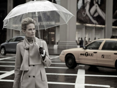A woman holding an umbrella while standing on the street.