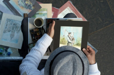 A person holding up an image of a man in a hat.