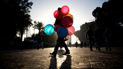 A man walking down the street with balloons in his hand.