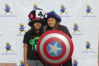 Two girls posing for a picture with their hats.