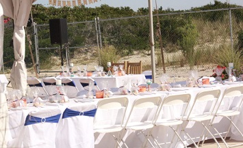 A group of tables with chairs and white table cloths.