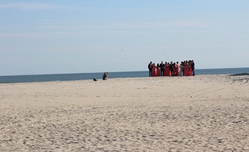 A group of people standing on top of a sandy beach.