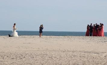 A woman holding onto a kite while standing on the beach.