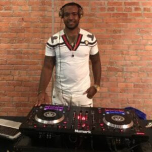 A man standing next to a dj 's equipment.