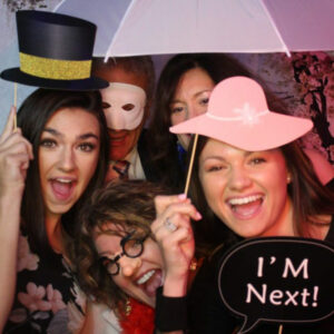 A group of people posing for a picture with hats and umbrellas.