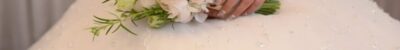 A close up of the bride 's bouquet and her wedding dress.