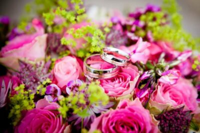 Two wedding rings sitting on top of a bouquet.