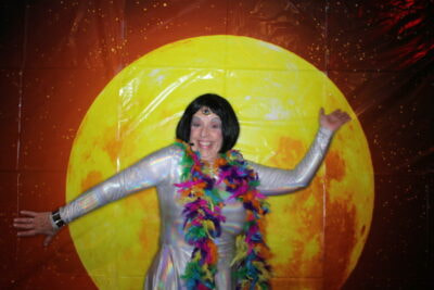 A woman in a silver outfit and colorful garland.