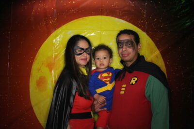 A man and woman holding a baby in batman costumes.