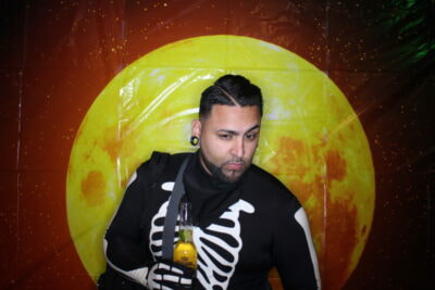 A man in skeleton costume holding a beer.