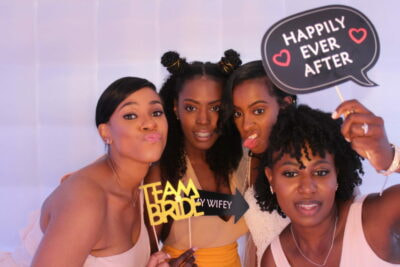 A group of women posing for a photo in front of a white wall.