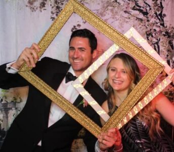 A man and woman holding up a picture frame.