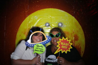 Two women posing for a photo with alien props.