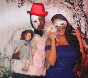 A man and woman posing for a picture with a doll.