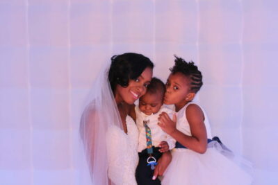 A woman holding two children and posing for the camera.