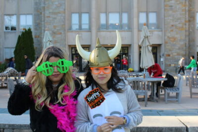 Two women wearing funny hats and glasses posing for a picture.