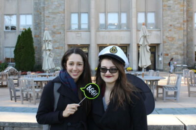 Two women posing for a picture in front of an outdoor restaurant.