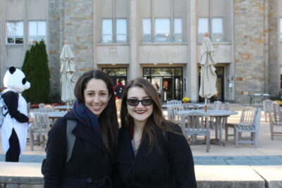 Two women standing next to each other outside a building.