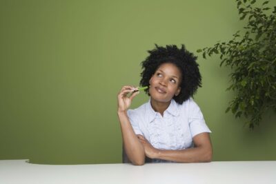 Woman thoughtfully holding a green item.