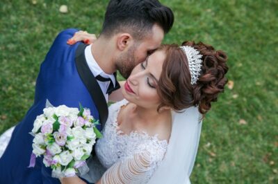 A man and woman kissing in front of some flowers.