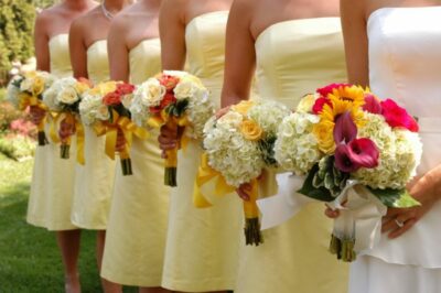 A line of bridesmaids in yellow dresses holding flowers.